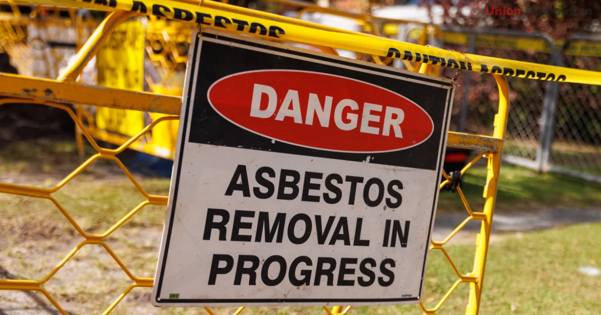 Danger sign with “Asbestos Removal in Progress” in fenced area.